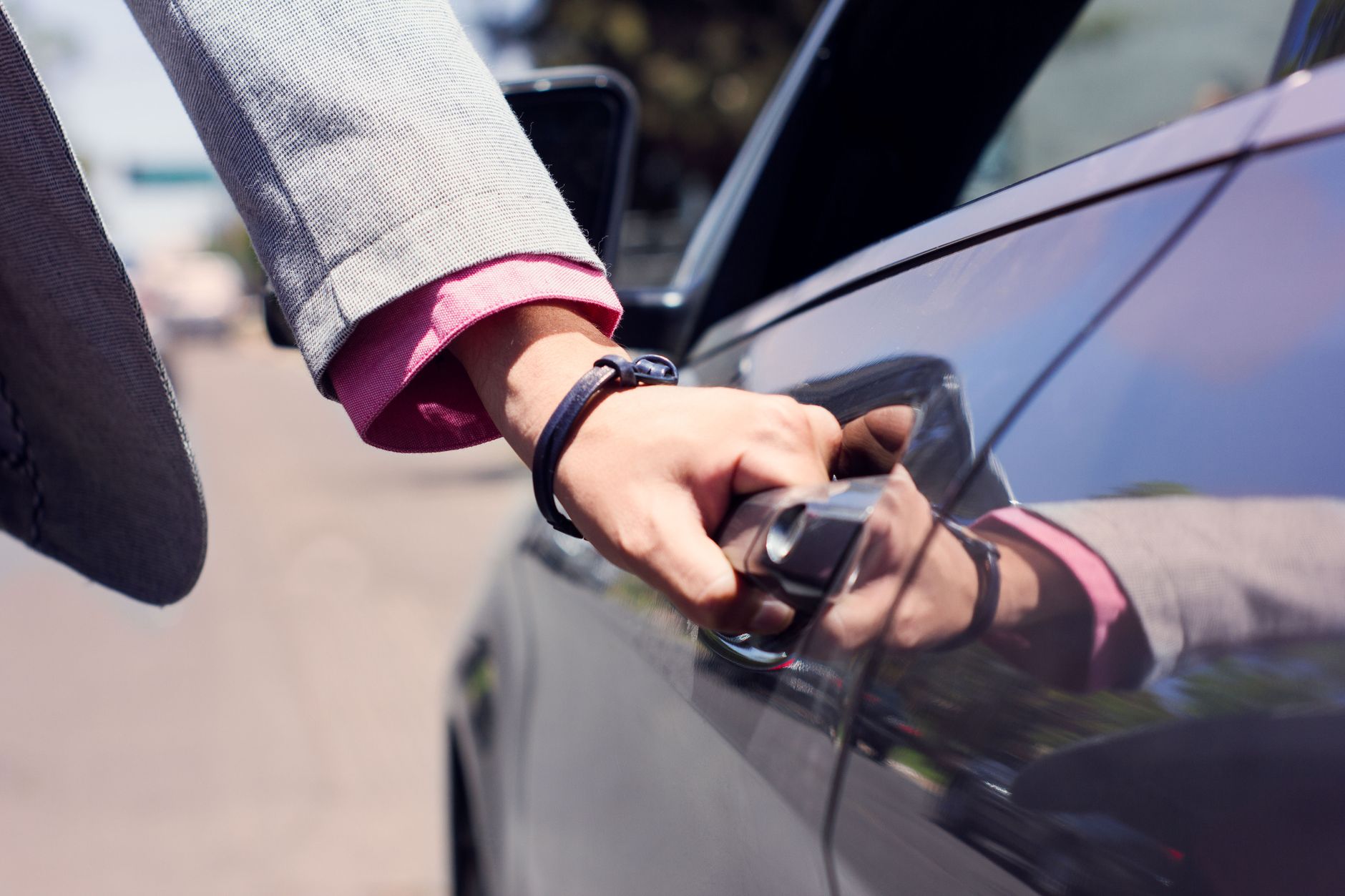 Close-up image of a hand opening a car door, highlighting business and transit themes.