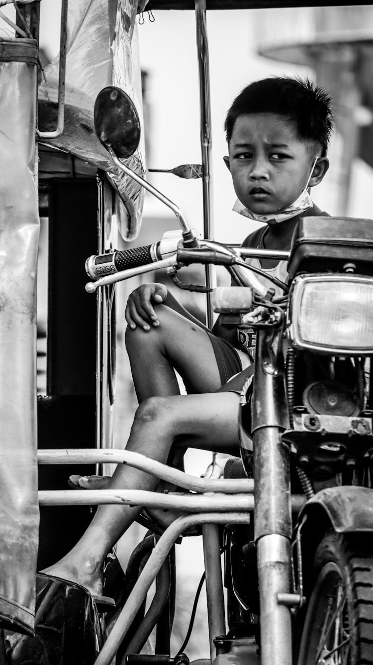 A Boy Sitting On The Tricycle