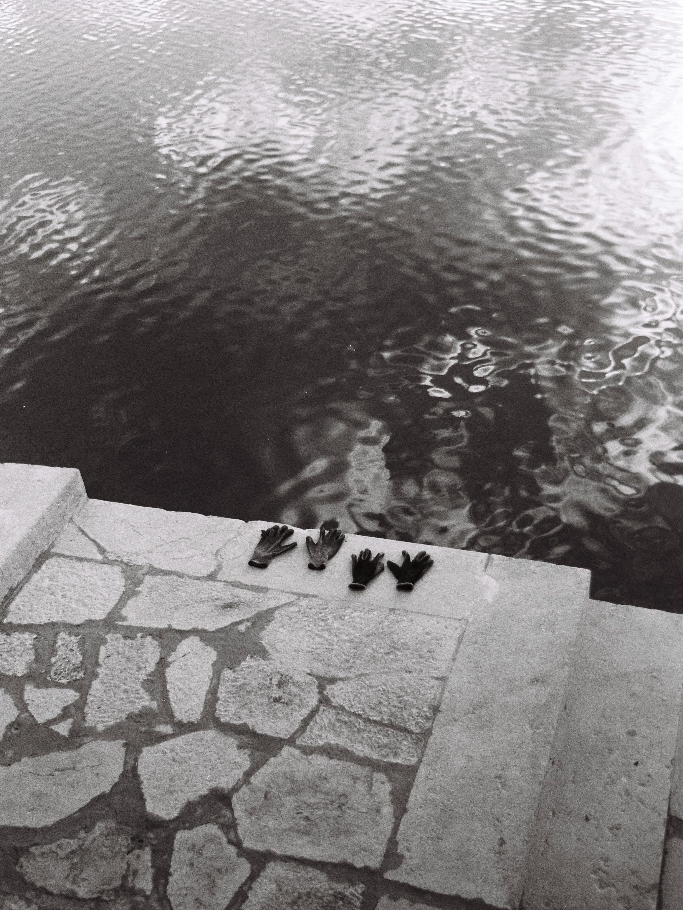Artistic black and white photo of gloves by water in Coimbra, Portugal.