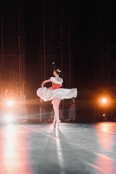 Ballerina gracefully spins during a live theater performance with spotlight.