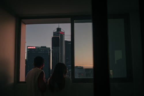 Man and Woman Looking out the Window in City 