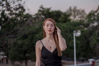 黄昏时分，一位身着黑色连衣裙、佩戴红色项链的时尚女士在户外摆姿，尽显优雅与自信