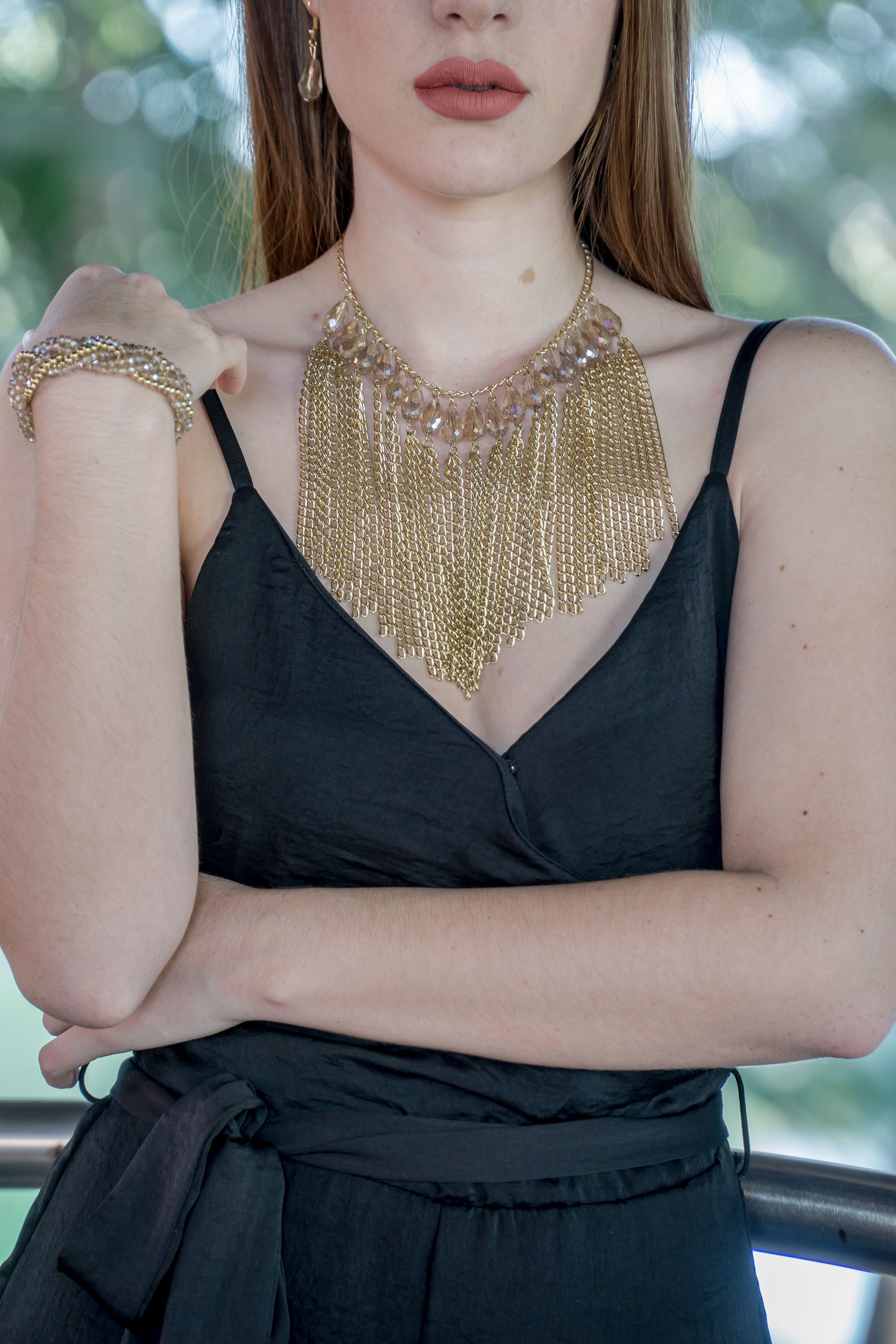 Mulher estilosa vestindo um elegante vestido preto e joias de ouro, exibindo um estilo de moda chique.