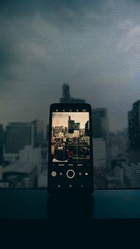 A smartphone screen capturing an urban cityscape through a dotted window, blending technology with city vibes.