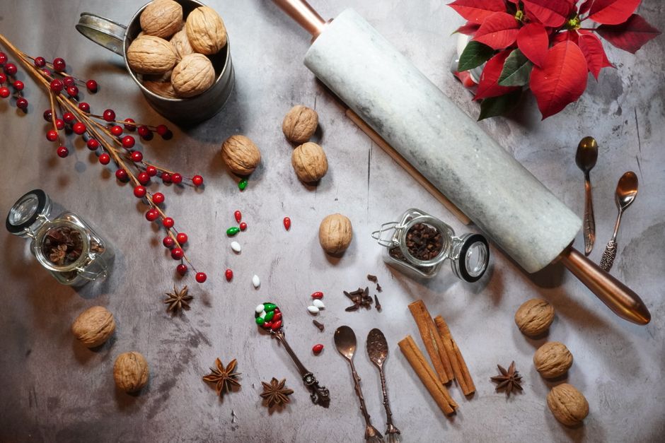 Top view of festive baking setup with walnuts, spices, and a marble rolling pin.