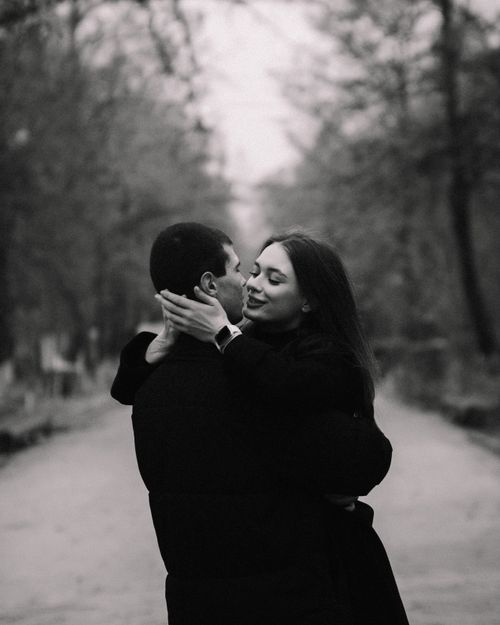 Free A black and white photo of a couple embracing in a forested path, showcasing love and connection. Stock Photo
