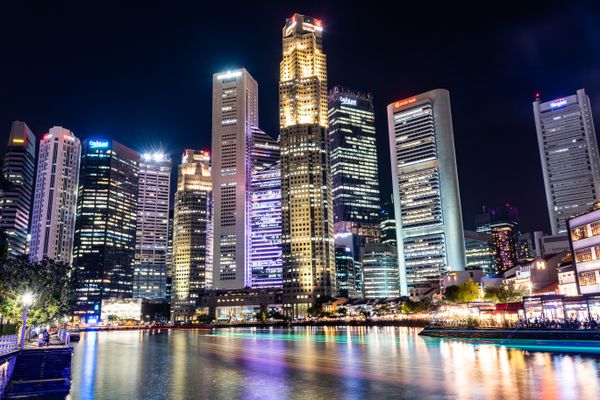 Vibrante horizonte de Cingapura com arranha-céus iluminados refletindo na Marina Bay à noite. Luzes icônicas da cidade.