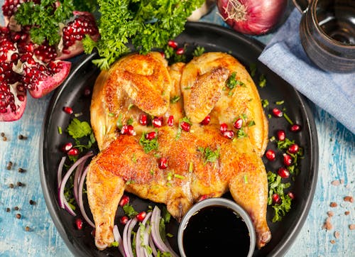 Top View of a Chicken Dish with Pomegranates and Kale