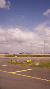 A clear day at an empty airport runway with yellow markings and blue sky.