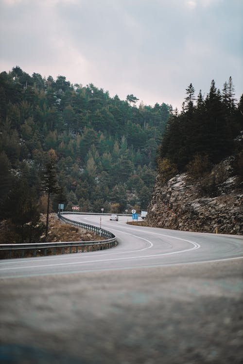 Gray Concrete Road Between Mountains with Green Trees