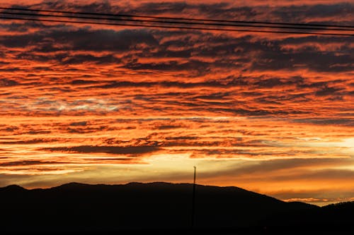 Silhouetted Mountains under a Bright, Dramatic Sky at Sunset 