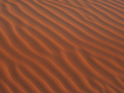 Free Waves of golden sand create mesmerizing patterns in Ras Al-Khaimah's desert at sunset. Stock Photo