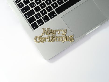 A festive Merry Christmas ornament on a laptop keyboard, perfect for holiday tech themes.