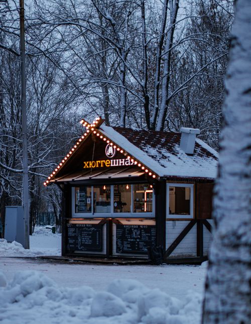 Free Illuminated food stand surrounded by snow in a serene winter forest. Stock Photo