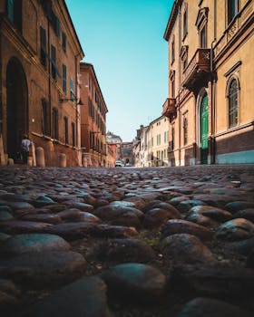 鹅卵石街道两旁，历史悠久的欧洲建筑在晴朗的天空下排列着