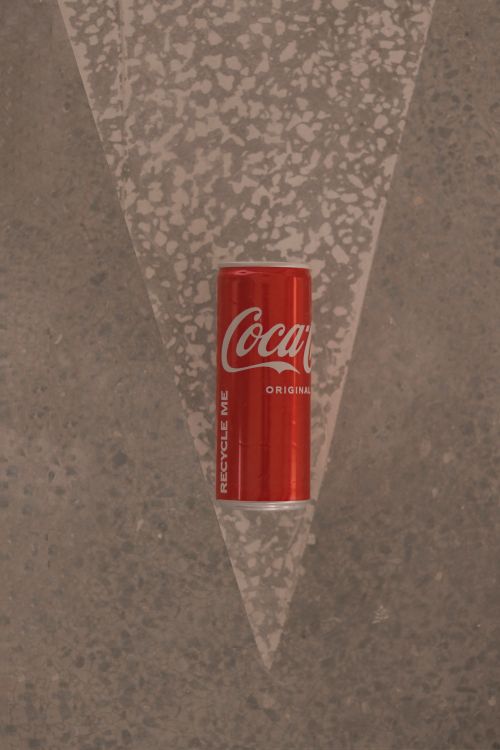 Free A Coca-Cola can is placed on a textured surface in a minimalistic composition. Stock Photo