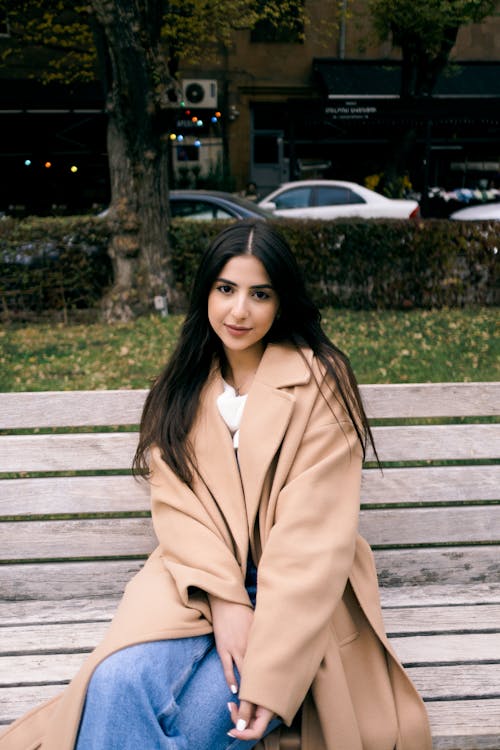 Beautiful Woman in Brown Coat Sitting on Wooden Bench