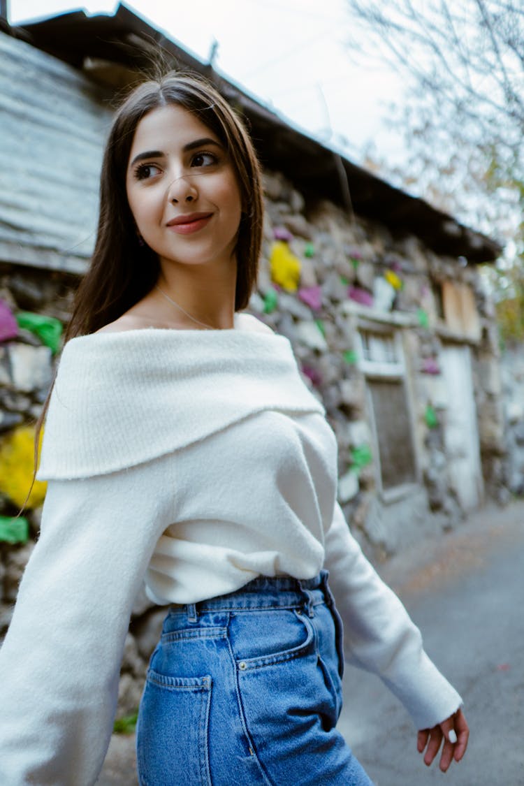 Young Woman Smiling In White Off Shoulder Sweater Walking On Street