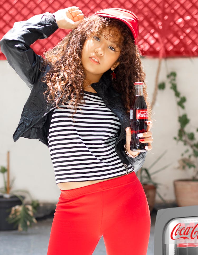 A Girl In Striped Shirt Holding A Coca-Cola Bottle