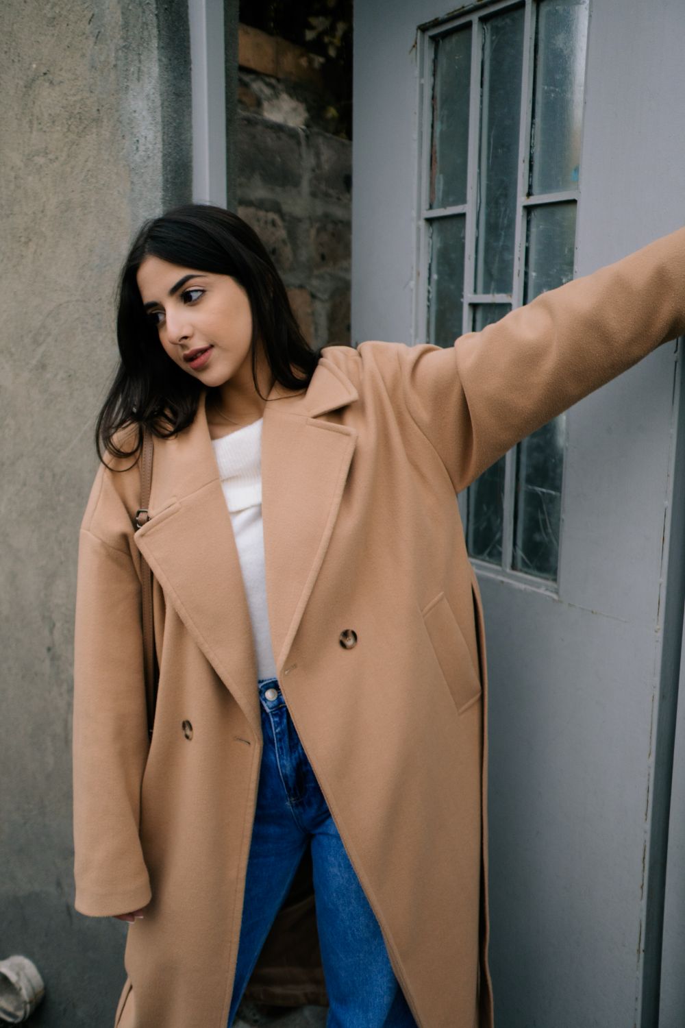 Woman in Brown Coat Standing Near White Wall · Free Stock Photo