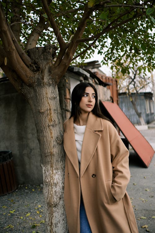Woman in Brown Coat Leaning on a Tree