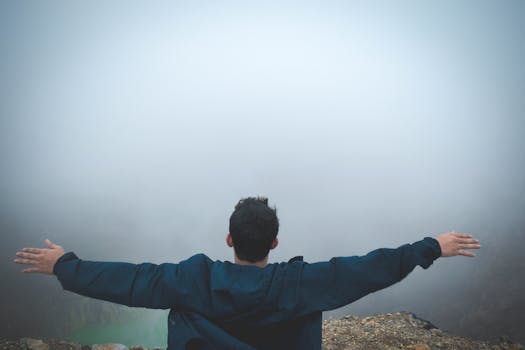 雾气缭绕的悬崖上，一名男子张开双臂，拥抱自由与自然