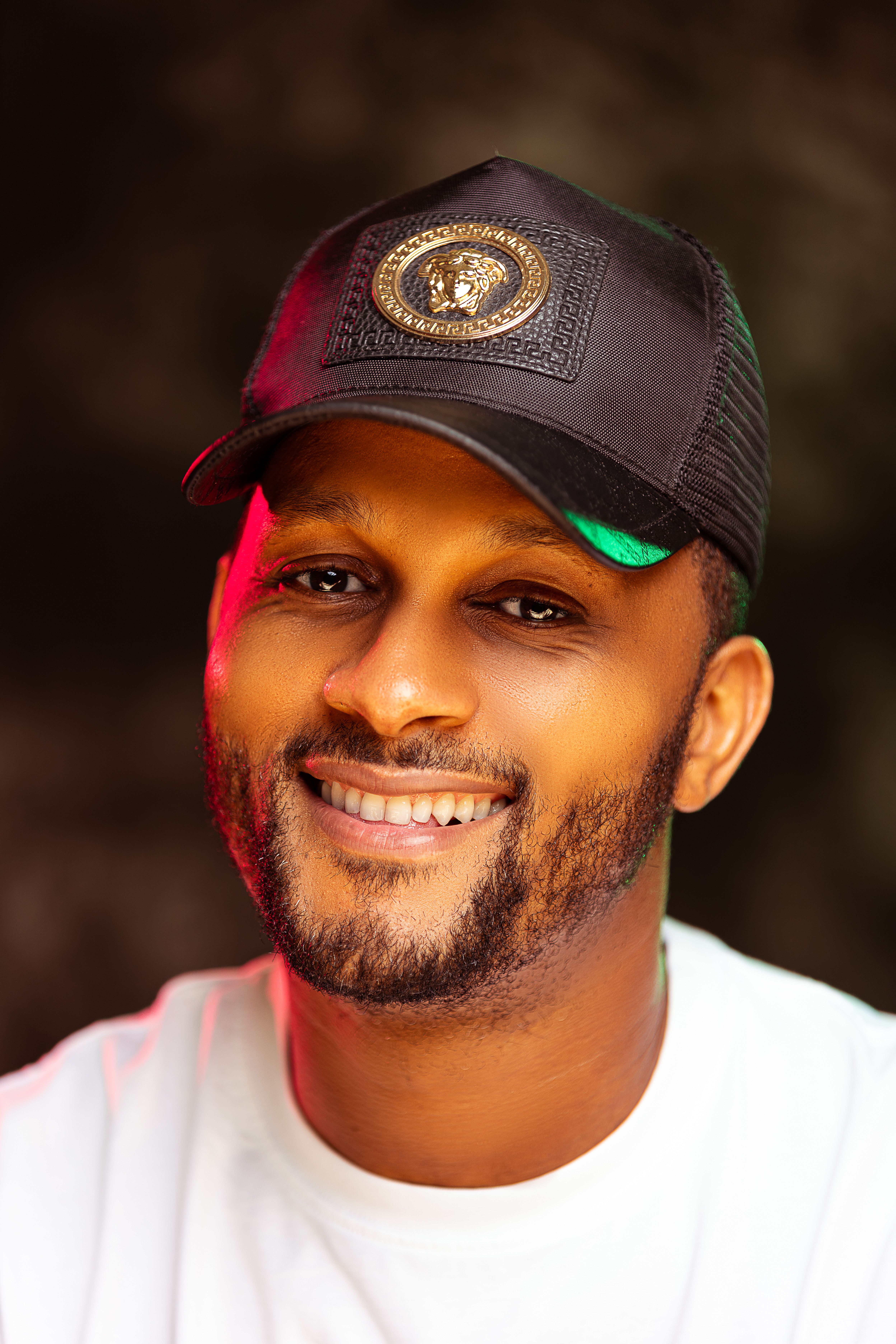 Close-up portrait of a smiling man wearing a black cap with a beard and mustache.