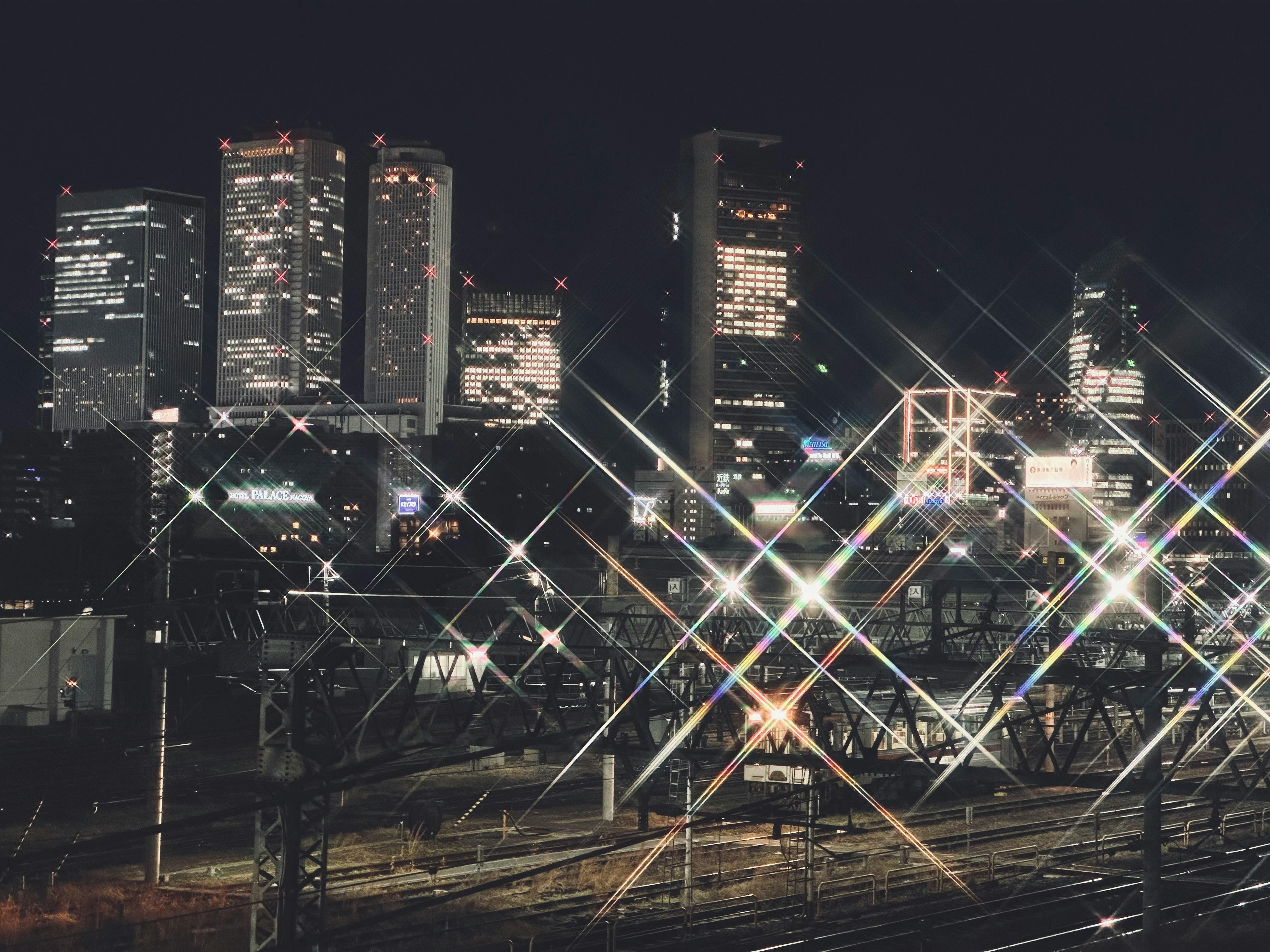 Dazzling view of Nagoya's skyline at night, showcasing illuminated skyscrapers and railway tracks.