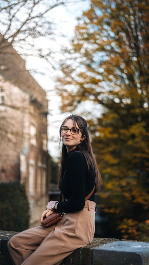 A Woman in Black Long Sleeves Sitting on a Concrete Bench while Looking Over Shoulder