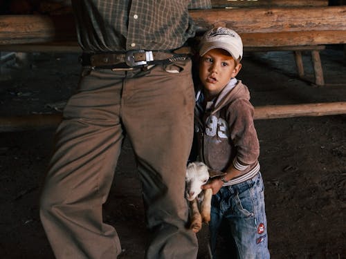 A Little Boy Holding a Baby Goat