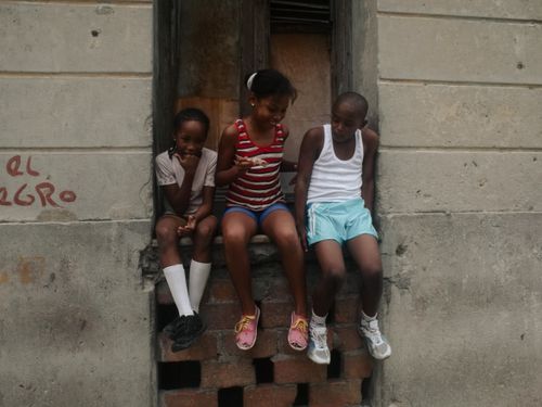 Free Three children sitting and laughing on a concrete wall, enjoying their time together. Stock Photo