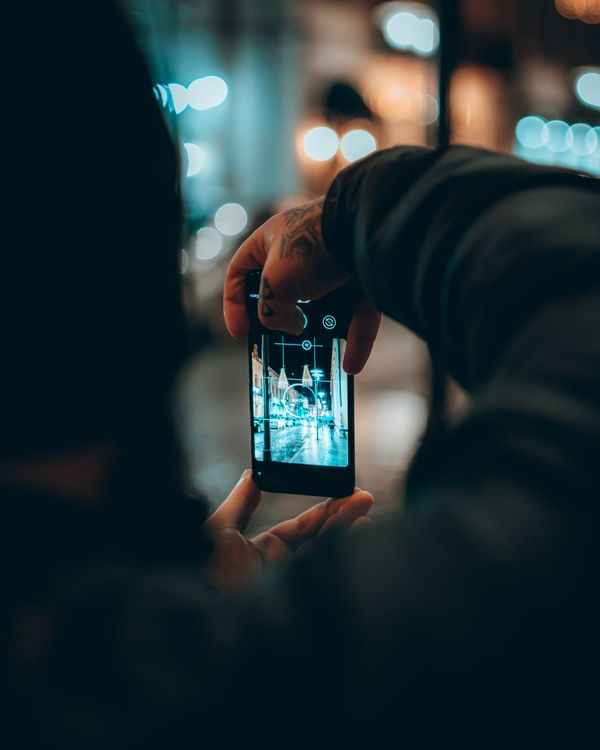 Free Close-up of a person photographing city lights at night in Kutaisi, Georgia using a smartphone. Stock Photo