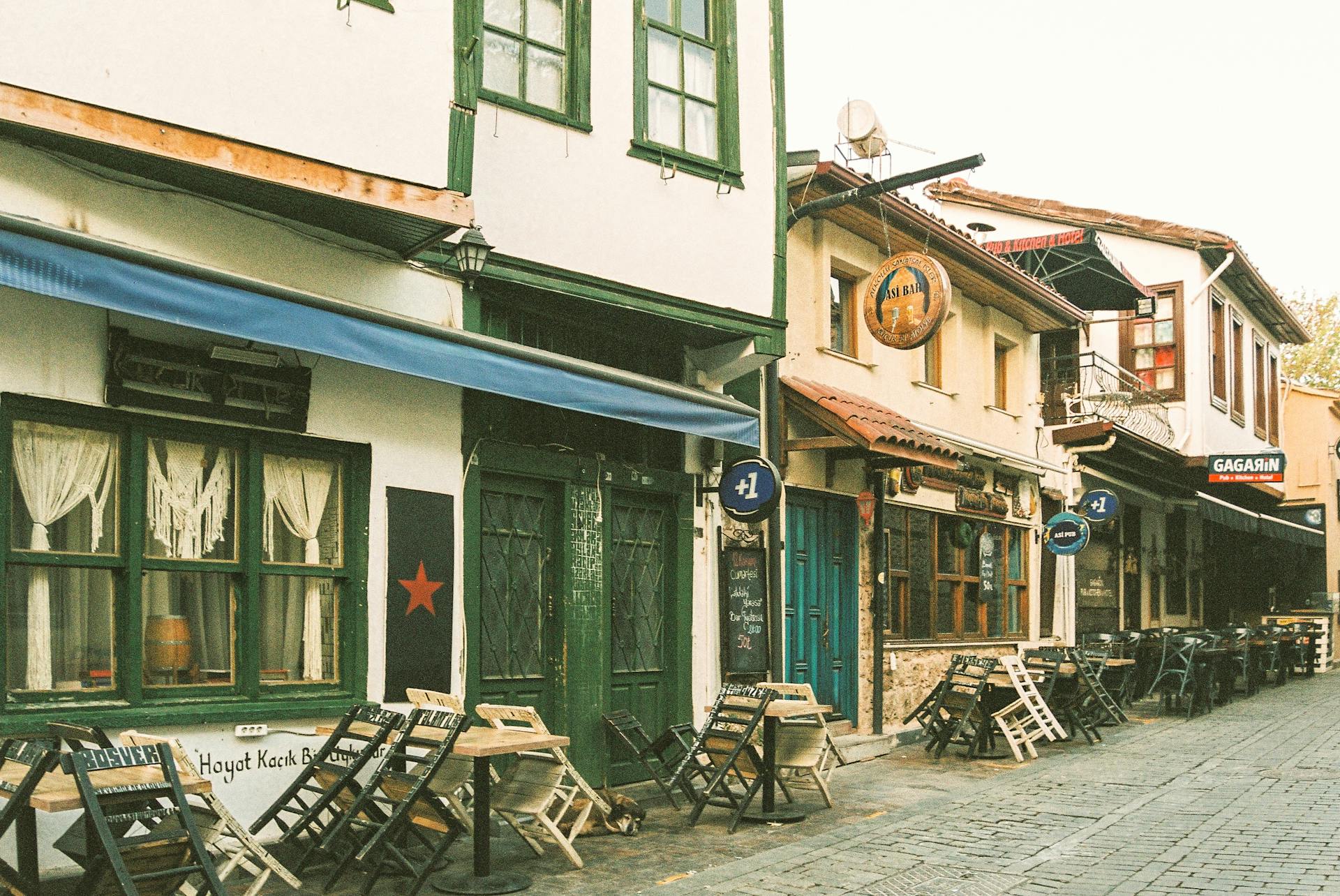 Vintage European street view with charming storefronts and outdoor cafes, offering an inviting ambiance.