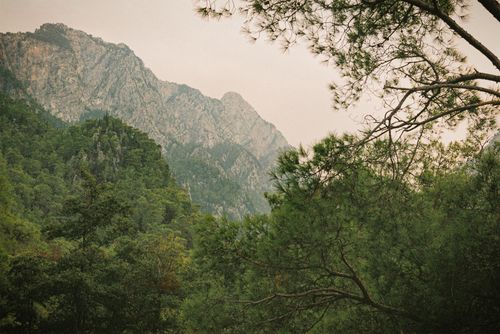 Free A beautiful rocky mountain landscape surrounded by lush green trees and cloudy sky. Stock Photo