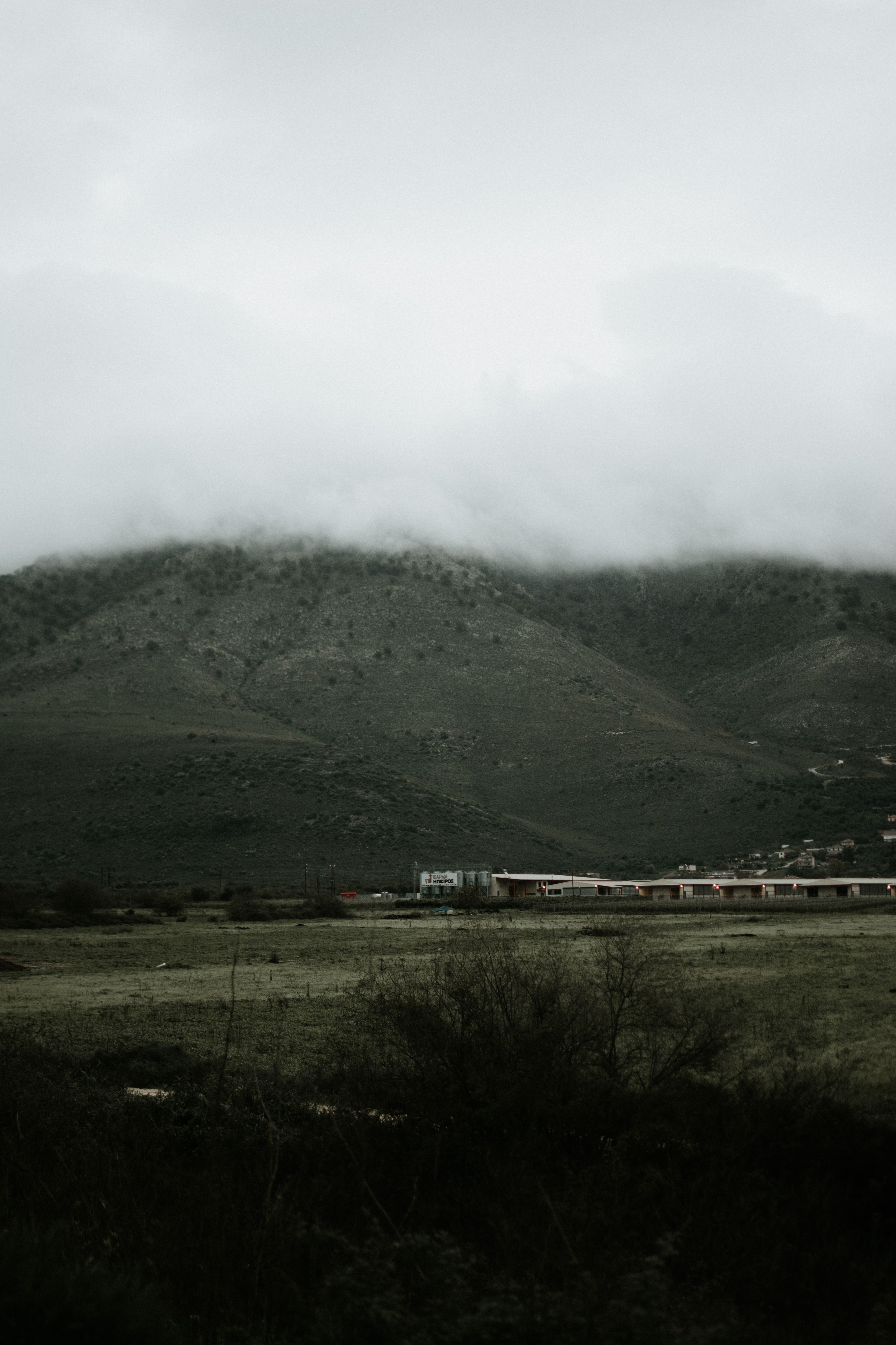 Serene foggy mountain landscape with clouds hovering over lush green hills creating a misty ambiance.