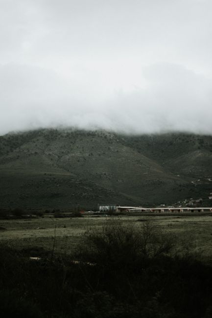 Serene foggy mountain landscape with clouds hovering over lush green hills creating a misty ambiance.