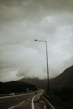 A deserted highway stretches under a dramatic cloudy sky, creating a moody atmosphere.