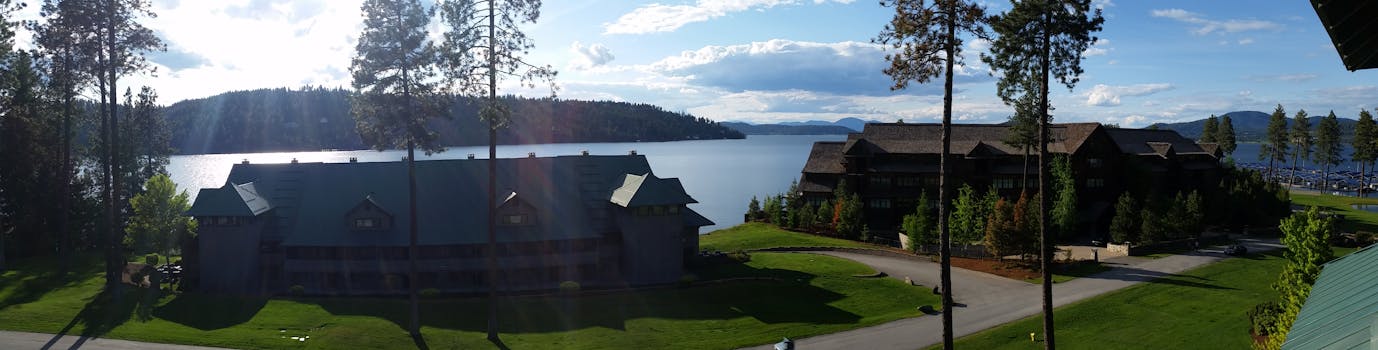 海滨度假村全景美丽，湖边有建筑，高大的树木矗立在夏日天空下