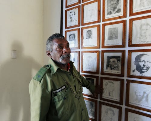 Military Veteran Standing By a Wall of Portraits