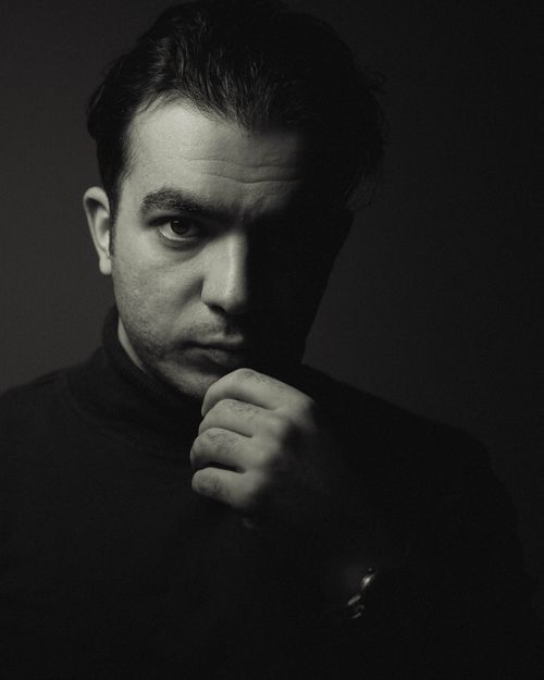 Free Moody monochrome portrait of a man with hand on chin, expressing deep thought. Stock Photo
