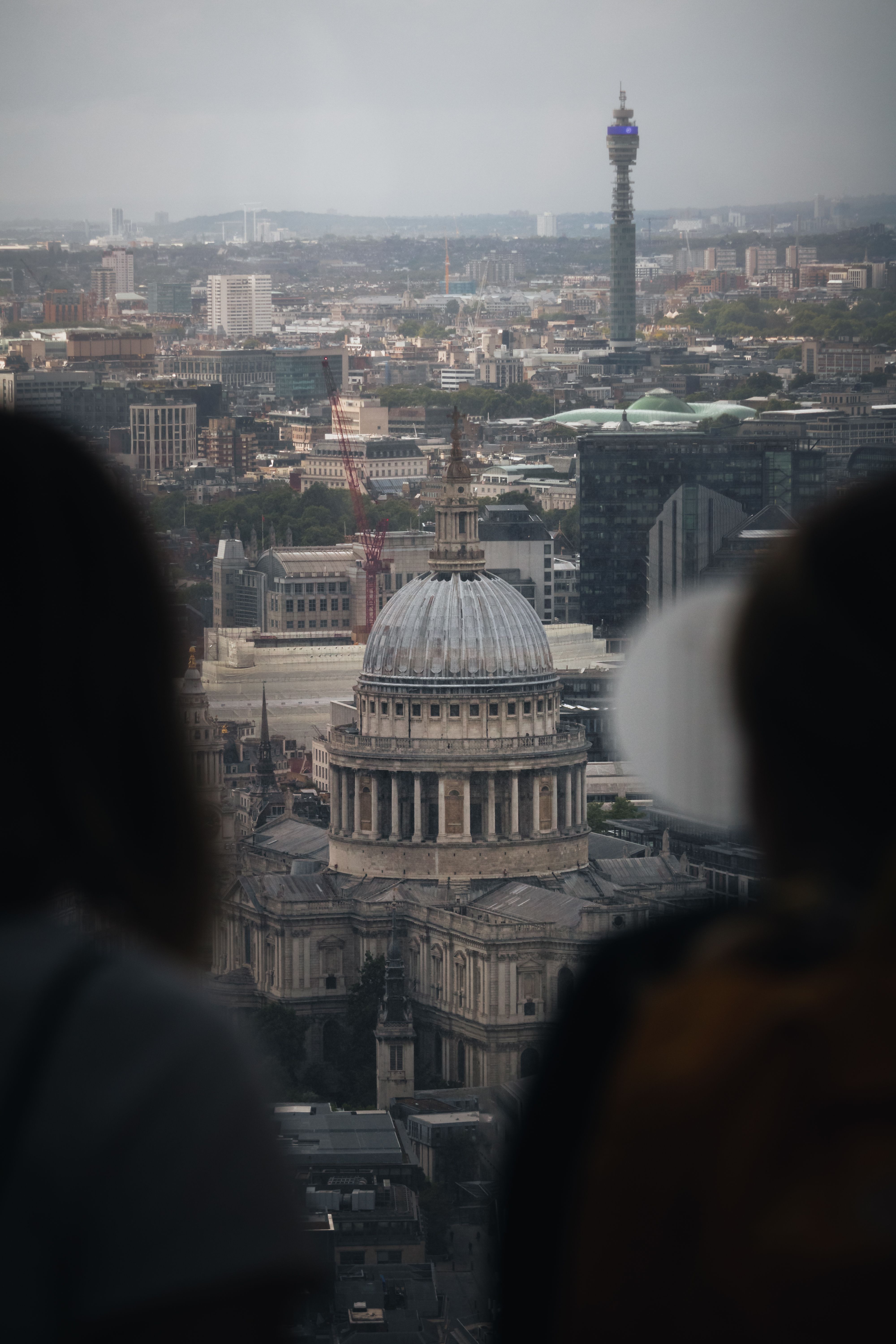 Stunning view of St Paul's Cathedral and London skyline with people silhouetted, captured from above.