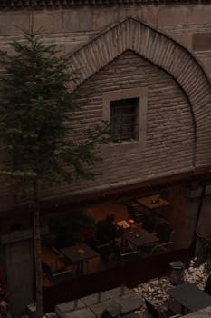 A cozy outdoor café scene beneath a rustic stone arch, capturing a quiet ambiance.