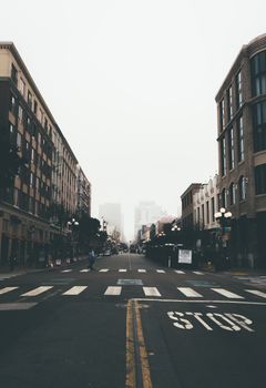 Misty urban street framed by symmetrical buildings and a foggy skyline.