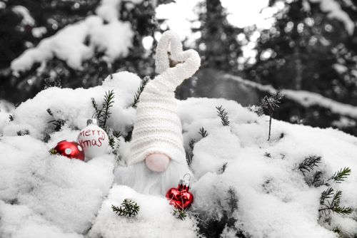 Free A charming gnome in the snow, surrounded by Christmas ornaments, spreads holiday cheer. Stock Photo