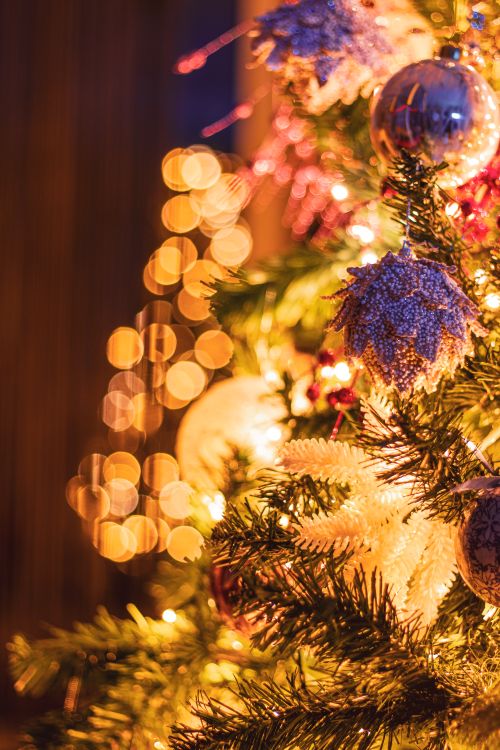 Free Close-up of a Christmas tree with glowing ornaments and bokeh lights. Stock Photo