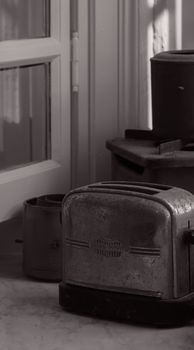 An artistic black and white photo of a vintage toaster in a classic kitchen setting.