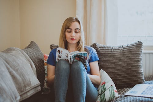 무료 책을 읽는 동안 소파에 앉아 여자 스톡 사진