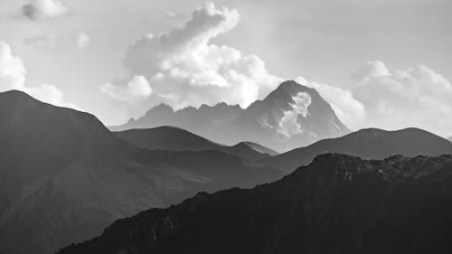 Grayscale Photo of Mountains under the Cloudy Sky