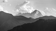 Grayscale Photo of Mountains under the Cloudy Sky