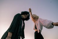 两个女人在黄昏时分，无忧无虑地享受着户外时光，她们面带微笑，举起双臂，愉快地摆出姿势